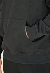 Svart sweatshirt med känguruficka, ribbade manschetter och nederkant, tillverkad av mjukt, texturerat tyg. Designen fokuserar på värme och komfort.