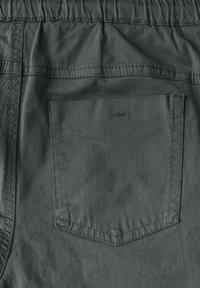 Grå shorts i lätt tyg med elastisk midja. Har en bakficka med rektangulär form och synlig sömnad.