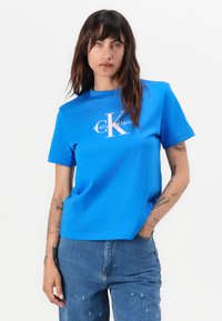 Tricou albastru cu mânecă scurtă, fabricat din bumbac, cu un logo alb Calvin Klein pe piept și gât rotunjit.