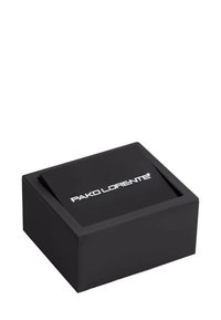 Czarny prostokątny pudełko o gładkiej powierzchni, z białym logo marki na górze. Prosty design i matowe wykończenie.