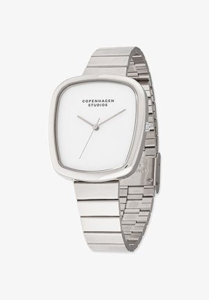 Montre carrée en argent avec un cadran blanc, dotée de fines aiguilles et d'un design minimaliste. Bracelet en acier inoxydable avec des maillons entrelacés.