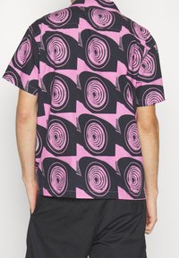 Lyhythihainen paita musta-pinkissä spiraalikuosisessa, rento malli ja kevyt kangas. Sopii arkikäyttöön.