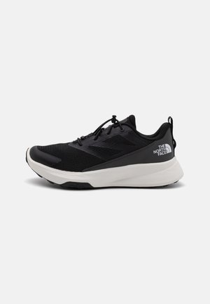 Black athletic shoe with a mesh upper, textured design, white midsole, and black outsole. Features laces and a logo on the heel.
