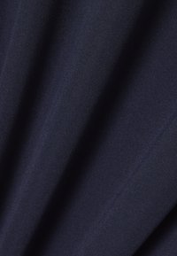 Tela azul marino oscura con textura fina y pliegues suaves que crean sombras y reflejos a lo largo de la superficie.