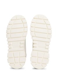 Semelles de chaussures en caoutchouc blanc avec des rainures profondes pour une traction optimale. Présente une surface texturée et des zones surélevées pour une meilleure adhérence. Marque visible sur le côté.