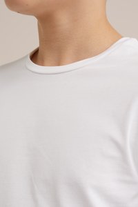 Bílý krátký rukáv tričko, design s kulatým výstřihem, hladká bavlněná tkanina, přiléhavý střih, jemná textura, žádné viditelné vzory nebo grafika.