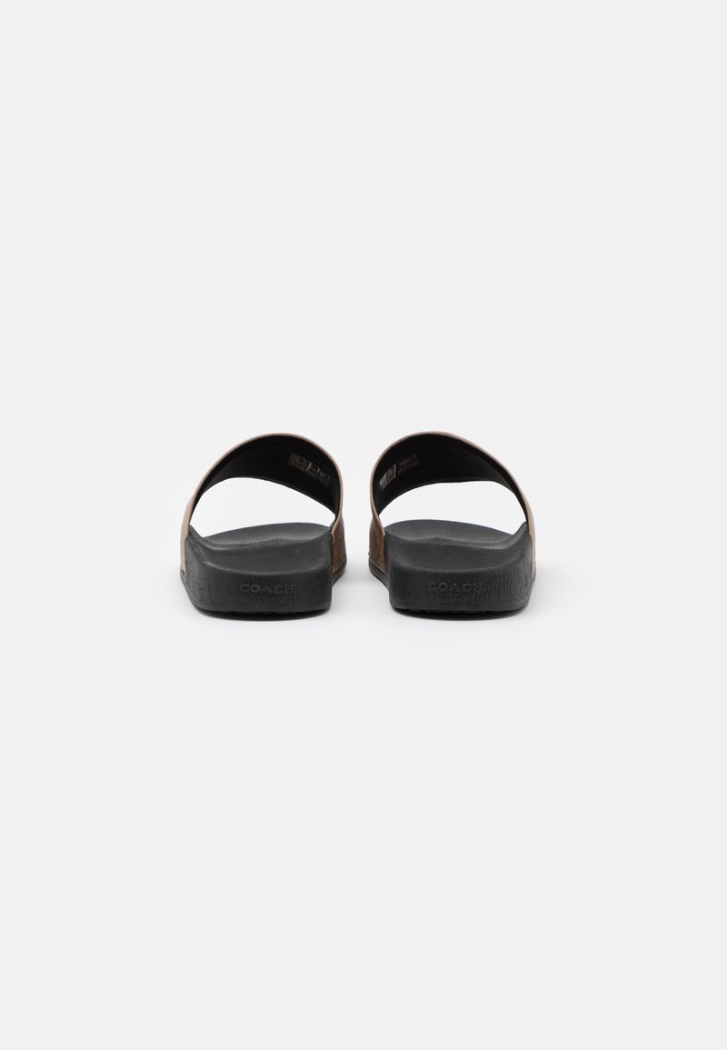 Brown suede sandals with two wide straps, open back, and textured black rubber soles. Features subtle branding on the sole.