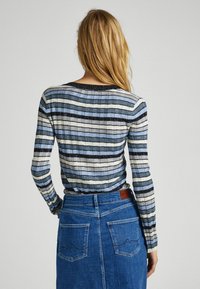 Sweter w paski, prążkowany, w odcieniach niebieskiego i szarego, z długimi rękawami i okrągłym dekoltem, w połączeniu z dżinsową spódnicą o wysokim stanie.