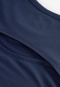 Haut de sport bleu marine avec une texture lisse, doté d'un design superposé et comprenant un logo en relief dans la partie supérieure.