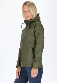 Giacca impermeabile verde oliva con cappuccio, cordini regolabili e tasche laterali con zip. Presenta una zip frontale e polsini elasticizzati.