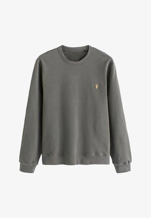 Hallhalli puuvillane dressipluus pika varrukaga, soonikuga kaeluse ja mansettidega, millel on rindkere peal väike kuldne tikand.