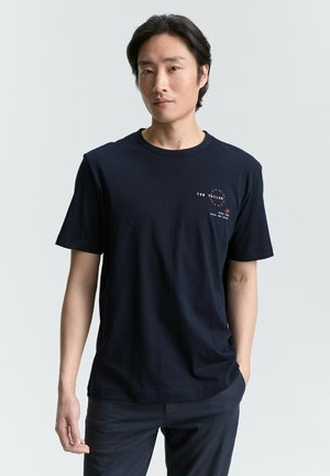 Navy cotton t-shirt with short sleeves and a round neckline. Features a printed logo design on the left chest area.