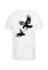 Hvid t-shirt med sort grafik af to krager i flugt, med teksten "IKKE BANGE" i et subtilt baggrundsmønster.