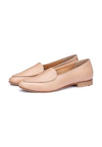 Mocassins en cuir nude avec un bout rond et des coutures décoratives. Talon en bois plat, texture lisse et design minimaliste.