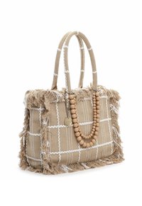 Beżowa pleciona torba typu tote z białym wzorem w kratę, frędzlami na krawędziach i podwójnymi uchwytami z liny; ozdobiona drewnianymi koralikami i zawieszką.