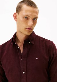 Bordeaux corduroy shirt met button-down kraag, subtiele textuur en klein geborduurd logo op de borst.
