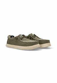 Zapatos verde olivo con una parte superior de tela texturizada, suela de goma color marrón claro y costuras decorativas. Presentan un diseño con cordones y un forro estampado.