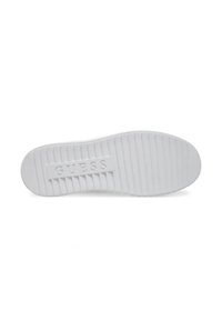 Semelle de sneaker en caoutchouc blanche avec une texture striée et le logo "GUESS" en relief sur un panneau rectangulaire lisse.