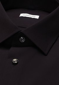 Schwarzes Hemd mit Kragen, zwei sichtbaren schwarzen Knöpfen und einem weißen Etikett mit der Aufschrift "seidensticker" im Kragen.