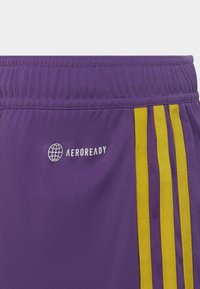 Lila Sportshorts mit gelben Seitenstreifen und einem weißen "AEROREADY"-Logo. Hergestellt aus leichtem Stoff mit einem elastischen Bund.