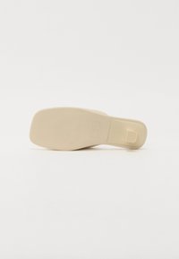 Semelle de chaussure beige avec une texture lisse, de forme rectangulaire, et de subtils stries horizontaux pour l'adhérence ; comporte une petite section de talon surélevée.