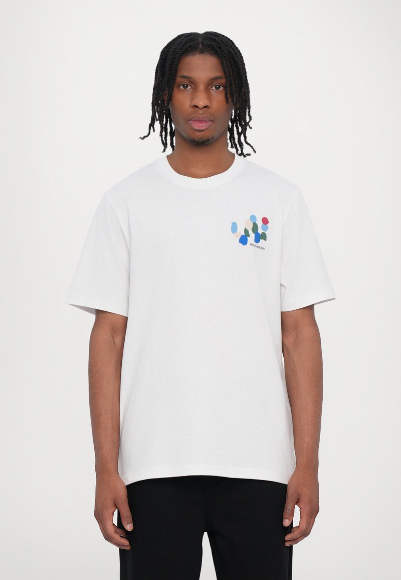 White cotton t-shirt featuring short sleeves, a crew neck, and a multicolored abstract design on the left chest area.