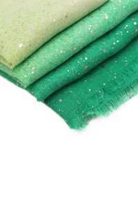 Quattro strati di tessuto leggero in tonalità di verde, con sitarelle dorate. I bordi sono frangiati per un effetto testurizzato.