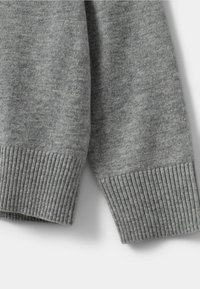 Pelēks adīts džemperis ar ribotām piedurknēm. Audums ir mīksts, demonstrējot gludu tekstūru un vienmērīgu krāsu visā virsmā.