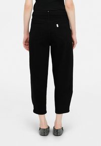 Pantaloni din denim negru cu o croială lejeră, talie medie și picioare scurte. Prezintă două buzunare la spate și un detaliu metalic cu logo.