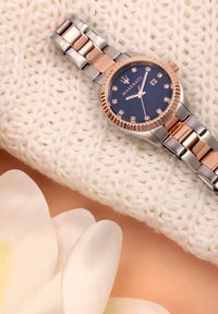Orologio Maserati con quadrante blu navy, dettagli in oro rosa e cinturino in acciaio inossidabile, con indicatori delle ore simili a diamanti e una finestra per la data.