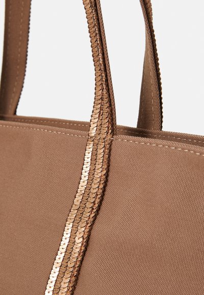 Sac fourre-tout en tissu marron avec deux poignées orné de sequins cuivrés le long des bords et de surpiqûres contrastantes sur le corps.
