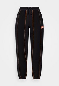 Zwarte joggingbroek met oranje zichtbare stiksels, elastische tailleband met trekkoord, elastische manchetten en een klein oranje logo-opnaad aan de zijkant.