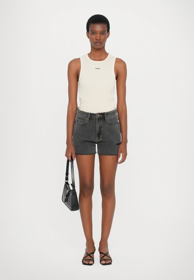 Light beige sleeveless top, black denim shorts with frayed hem, black handbag, and strappy black sandals. Simple, fitted design.