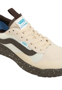 Beige i smeđi tenisice od antilopa i mreže. Imaju plave akcentne boje, bijele vezice i točkasti smeđi potplat. Uključuju petnu traku.