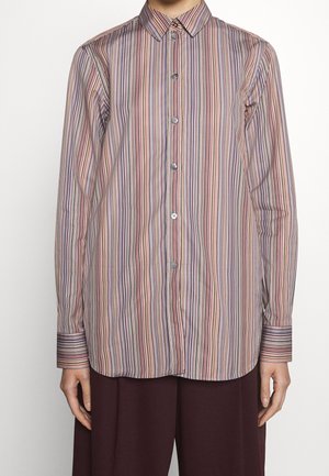 Chemise à manches longues boutonnée avec des rayures verticales multicolores dans des tons de rouge, bleu et beige, portée avec un pantalon foncé.