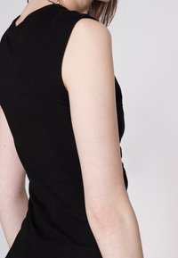 Top nero aderente senza maniche con una superficie liscia e scollatura arrotondata, che mette in risalto una semplicità elegante nel design.