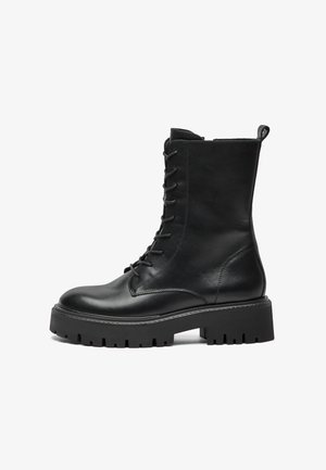 Zwarte leren veterschoenen voor de strijd met een dikke profielzool, enkellange schacht en een trekband aan de achterkant tegen een witte achtergrond.