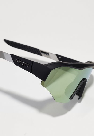 Óculos de sol Gucci preto e prateado com uma grande lente verde, design angular e hastes texturizadas. Apresenta a marca no aro.