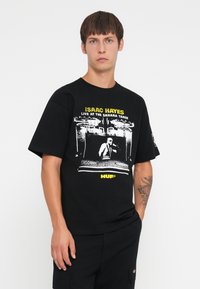 Sort bomulds t-shirt med et grafisk tryk af Isaac Hayes og gul tekst. Korte ærmer og en afslappet pasform. Enkel design og tekstur.