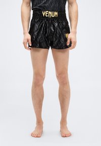 Μαύρο αθλητικό σορτς με γυαλιστερό φινίρισμα, υφή υφάσματος, λογότυπο VENUM σε χρυσό στη μέση και γραφικό λιονταριού στο τελείωμα.