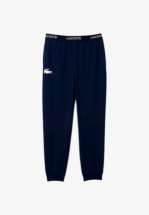 Pantalones joggers azul marino con cinturilla elástica que presentan el logo en blanco "Lacoste" y un pequeño cocodrilo blanco en la pierna izquierda.