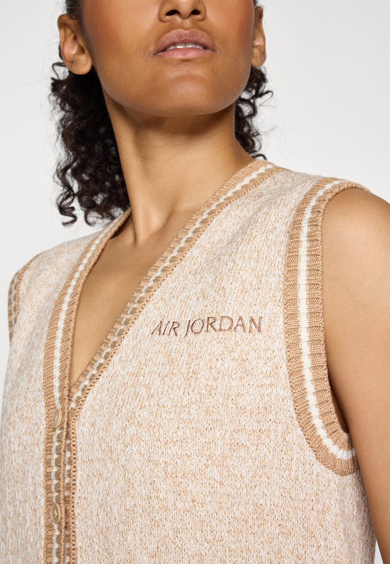 Beige gestrickte Weste mit Rippbesatz und braunen Akzenten, mit einem Knopfverschluss und "AIR JORDAN" auf der Brust gestickt.
