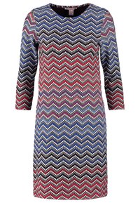 Šaty s dlouhým rukávem, zdobené cikcak vzorem v odstínech modré, červené a černé barvy, ozdobené kulatými flitry pro texturu a lesk.