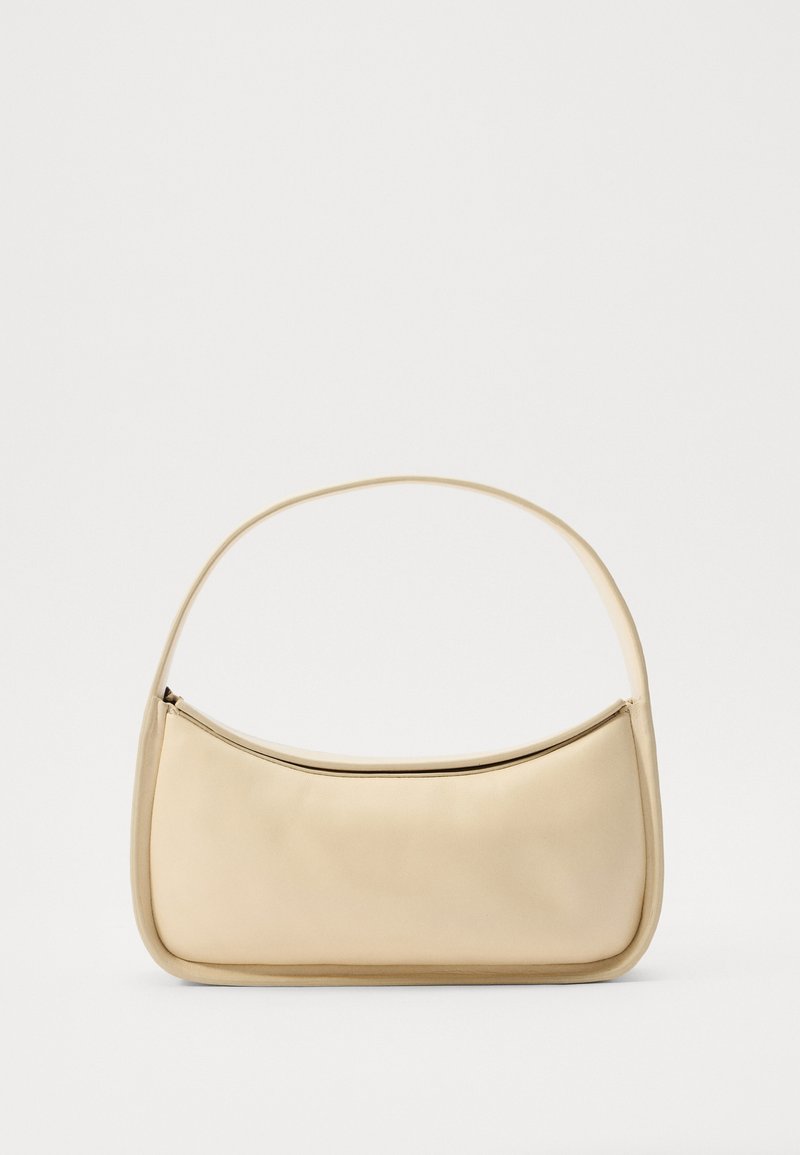 Beige kožená kabelka s hladkým povrchem, zakřiveným tvarem, jedním horním uchopem a zipovým uzávěrem podél horního okraje. Minimalistický design.