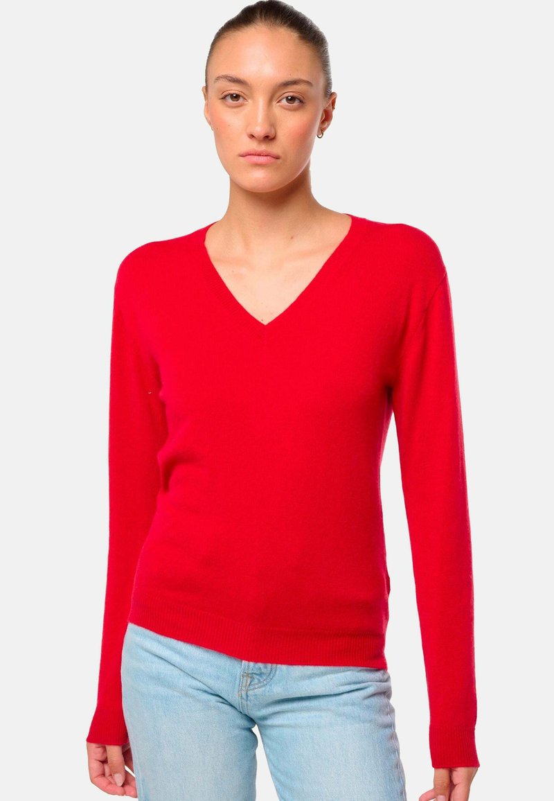 Pull rouge en V en tissu tricoté doux. Il possède des manches longues, des poignets et un ourlet côtelés, avec une coupe ajustée.