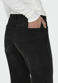Zwarte denim jeans met een klassiek vijf-pocket ontwerp, een mid-rise pasvorm, en zichtbare stiksels langs de zakken, gecombineerd met een strakke top.