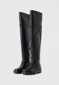 Over-the-knee black leather boots with a sleek design, featuring side zippers, a subtle gold accent, and chunky soles.