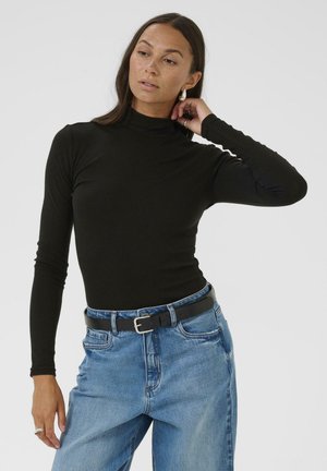 Un haut noir en jersey à manches longues et col roulé, associé à un jean en denim bleu clair taille haute et une ceinture noire.