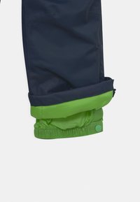 Navy wasserfeste Hose mit elastischem grünem Bund. Das Material ist glatt mit einem leichten Glanz. Der Bund hat einen Druckknopf und einen sicheren Sitz.