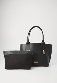 Sac fourre-tout noir en matériau souple semblable au cuir, avec deux poignées et une étiquette en métal. Comprend une petite pochette noire avec fermeture éclair et bord en cuir.